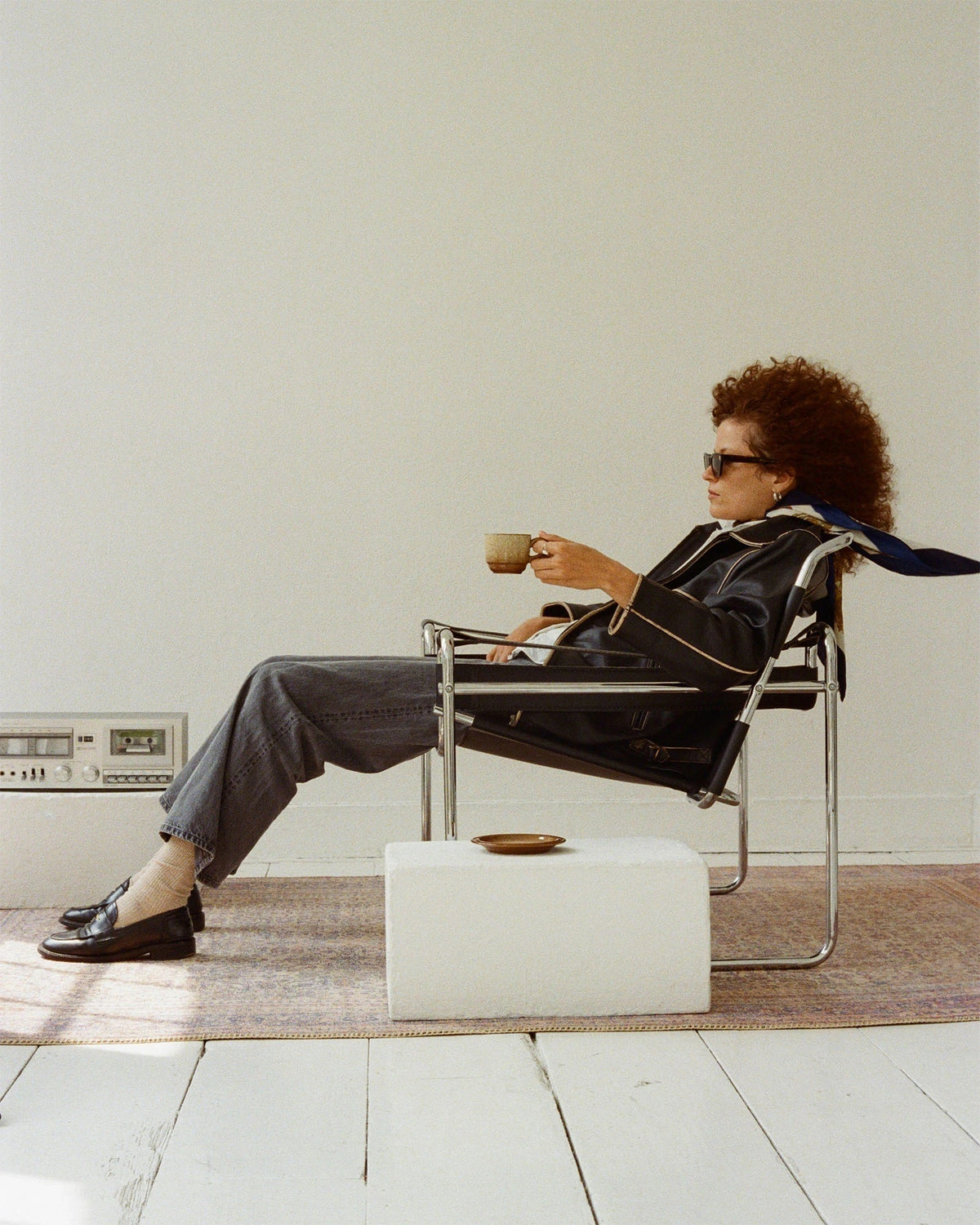 Ari Westphal sitting on a vintage chair with a coffee mug in her hand