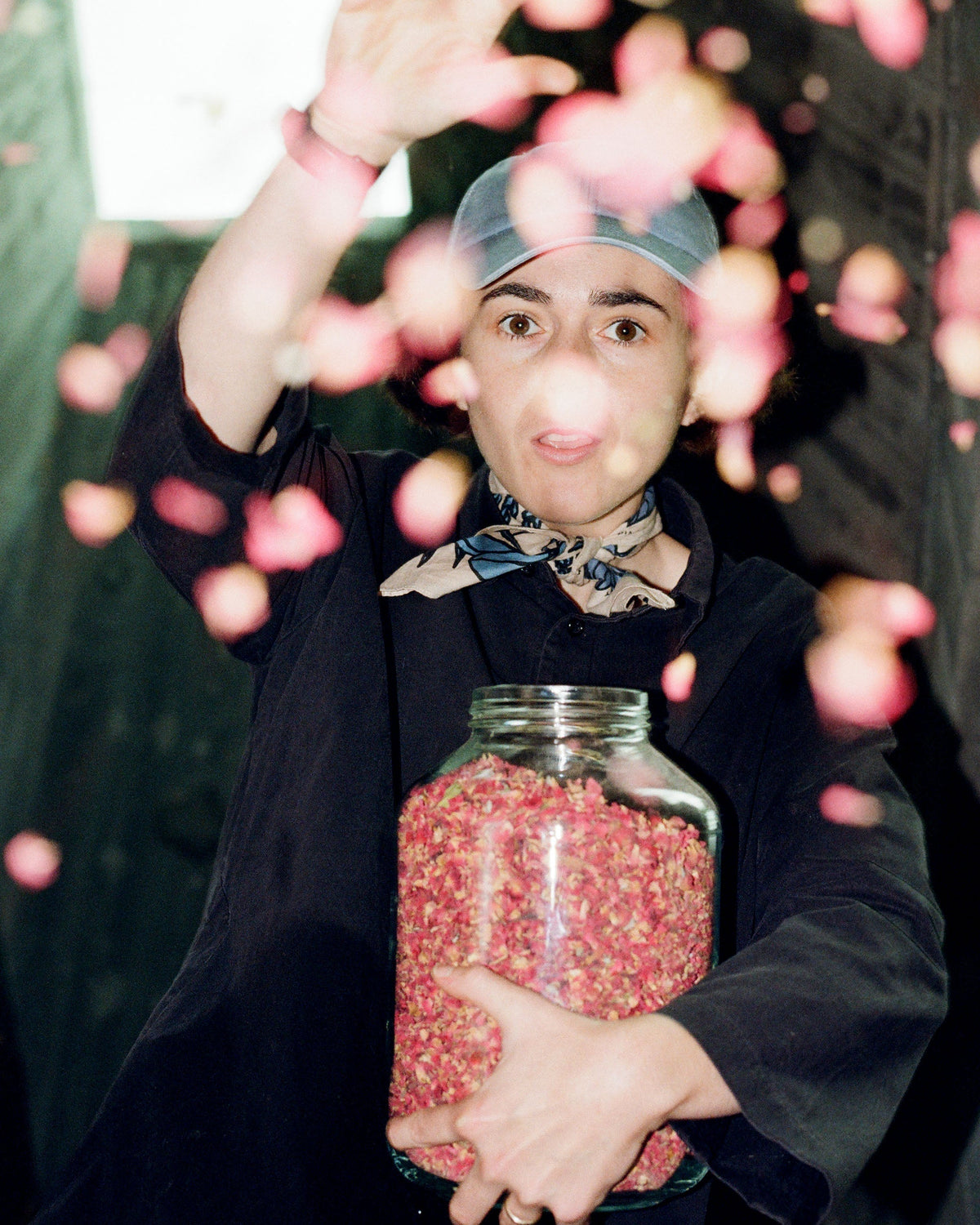 Carolyne Lane holding a jar full of coffee flowers throwing them into a camera