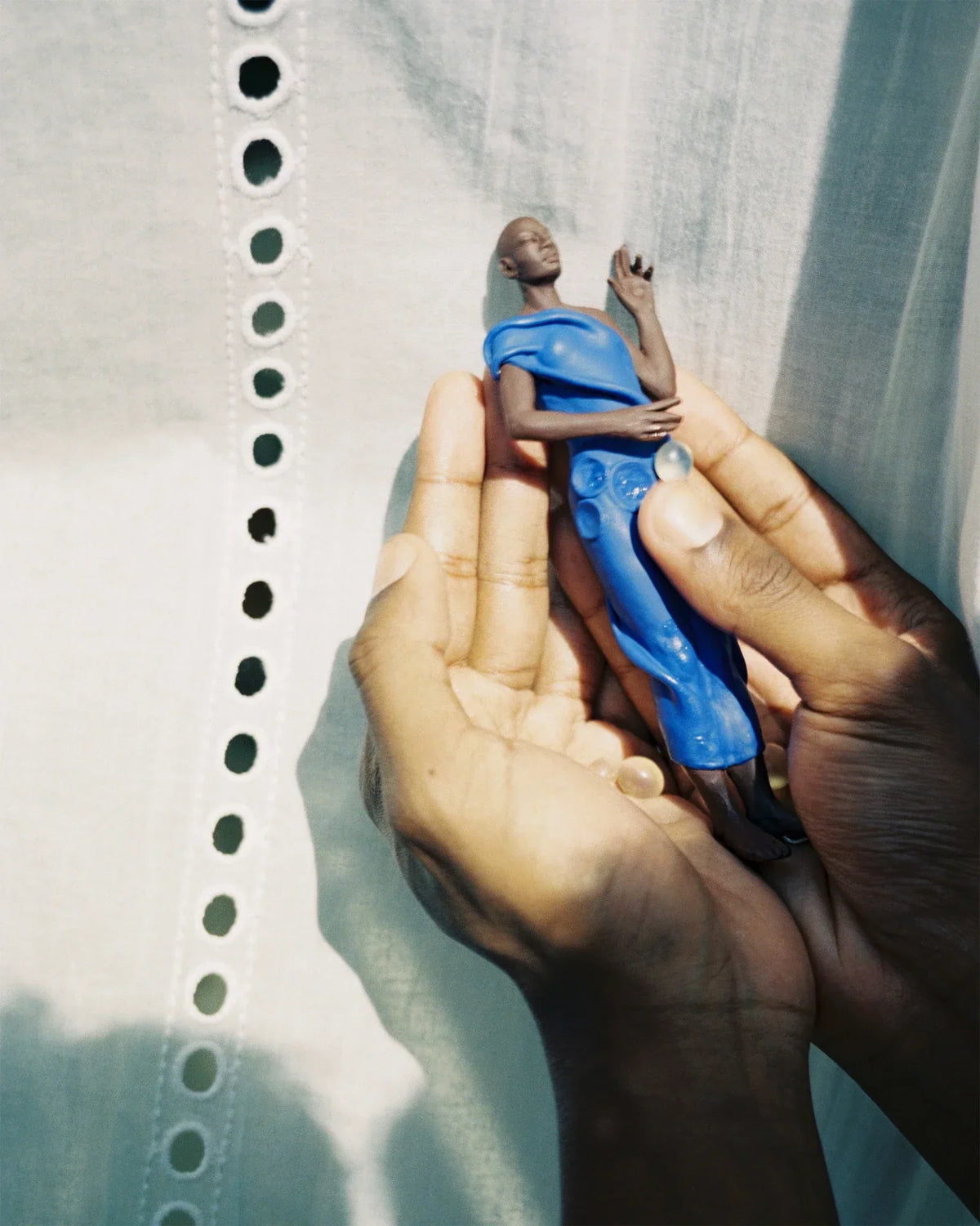 A sculpture by Ekaterina Kovalenko held in hands against a fabric backdrop