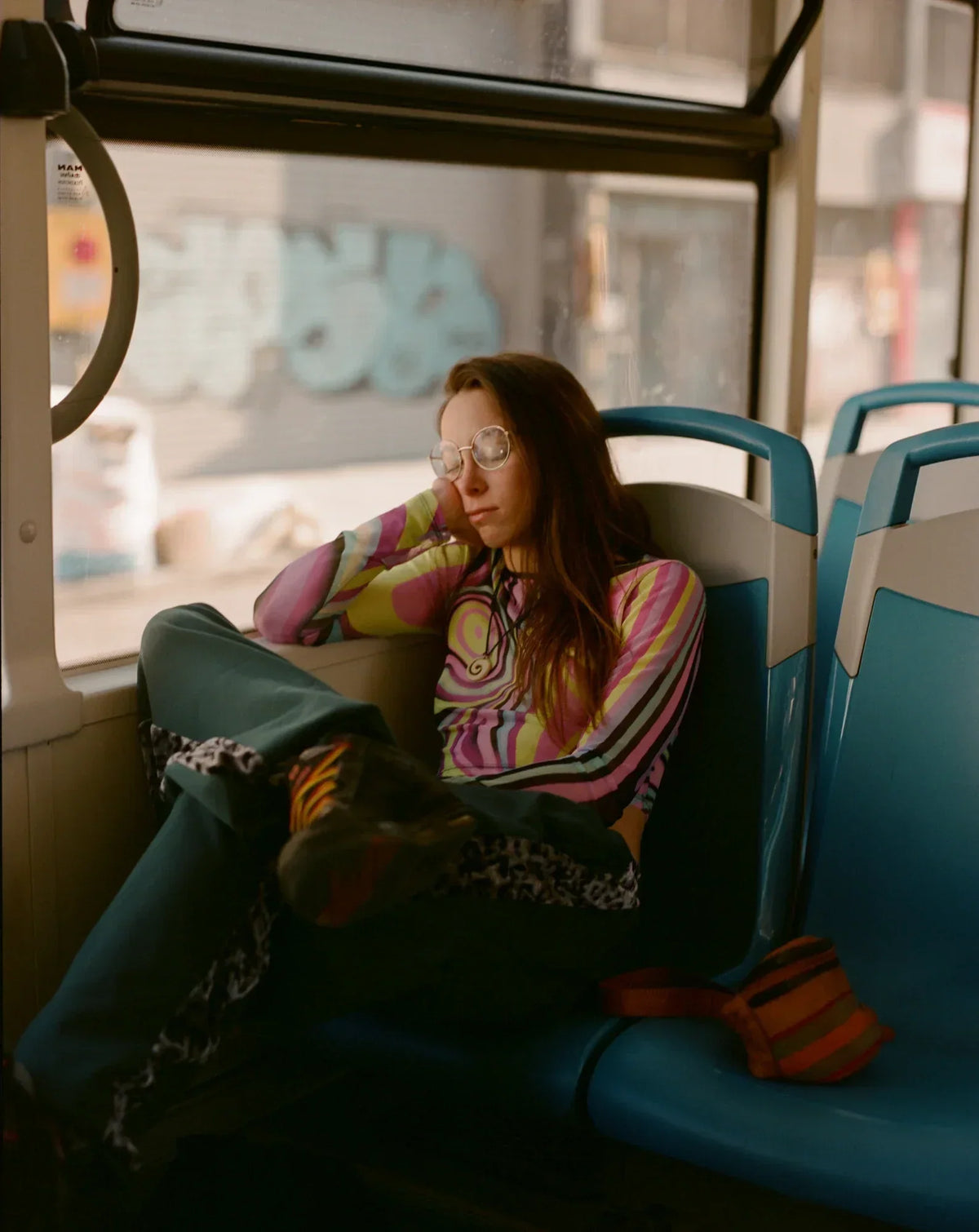 A young woman sleeping in a bus with her leg folded over the other one