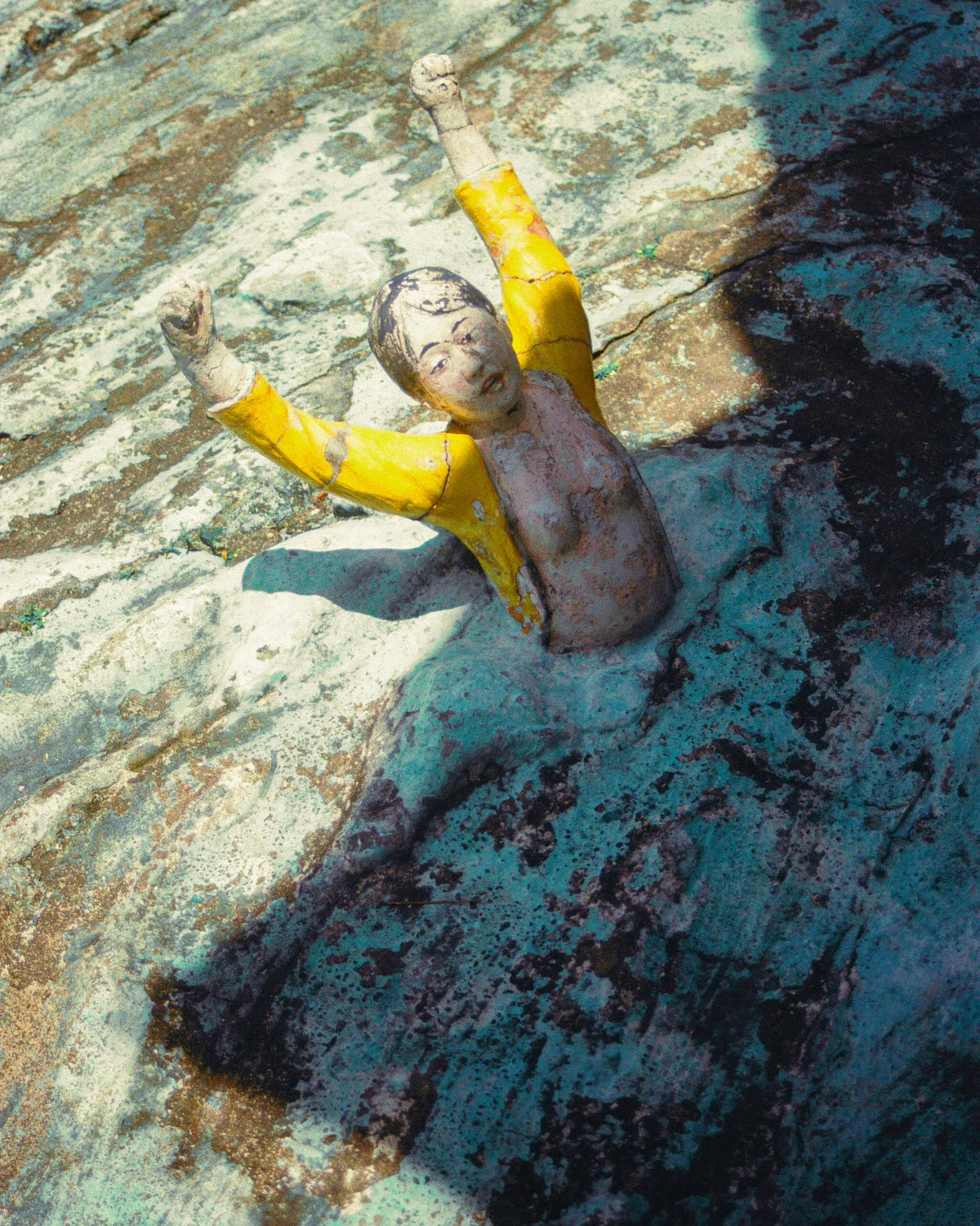 A strange statue of a woman pointing out of the rocks